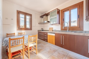 A kitchen with wooden cabinets, a built-in stove, a window, and a dining table with chairs.