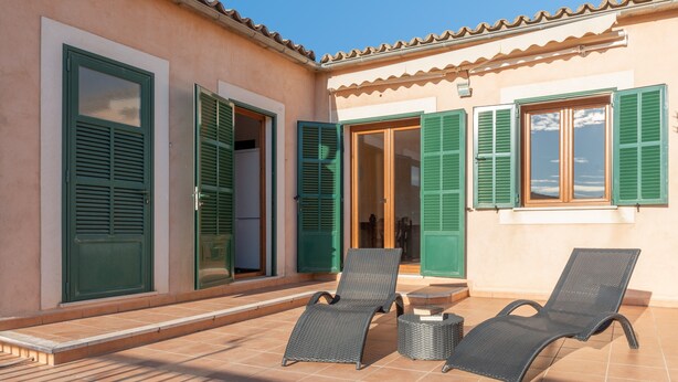 A building with green shutters, a tiled patio, and two lounge chairs. - Cosy Holiday Apartment with Wi-Fi, Air Conditioning and Terrace (Binissalem)