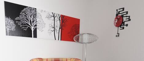 Un sillón escocés en una habitación con una lámpara de pie moderna y arte abstracto en la pared.