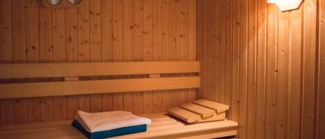 Eine Holzsauna mit Bänken und einem an der Wand befestigten Thermometer.