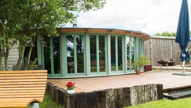 A covered patio area with a wooden deck, a bench, and a potted plant. - Ferienhof - Weites - Land, large apartment with terrace, garden and children's playground (Stadtkyll)