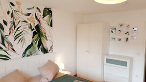 Une chambre avec deux lits, une armoire, un bureau et un mur décoré de tableaux encadrés.