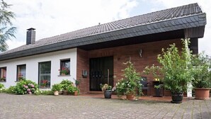 Een twee verdiepingen tellend huis met een bakstenen gevel, een pannendak en een geplaveid oprit.