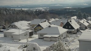 Een woonwijk met besneeuwde huizen en een bergachtig achtergrond.