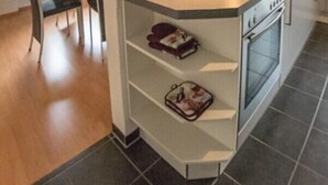 Een moderne keuken met een centraal kookeiland, een ingebouwde oven en een eethoek met een tafel en stoelen.
