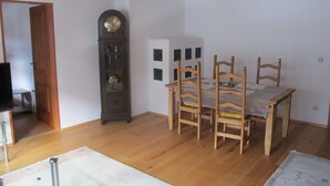 Ein Essbereich mit Holztisch und Stühlen, einer Wanduhr und einer Tür zu einem anderen Raum.