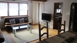 Ein Wohnzimmer mit einer Couch, einem Fernseher und Holzmöbeln.