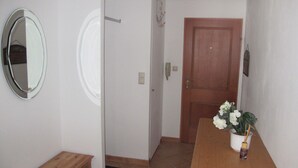 Ein Flur mit einer hölzernen Bank, einem Spiegel, einer Tür und einem Blumentopf mit Blumen.