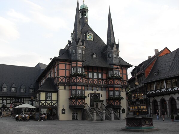 Un edificio histórico con una imponente torre de reloj y una fachada tradicional de entramado de madera.