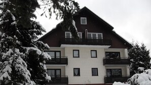 Ein mehrstöckiges Gebäude mit einer symmetrischen Fassade, Balkonen und einer verschneiten Landschaft.