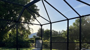 A covered swimming pool with a patio area, surrounded by a metal fence and trees. - VILLA BELLY :-) heated pool. free WIFI, very private, Garage, BBQ, Kings Lake (Naples)