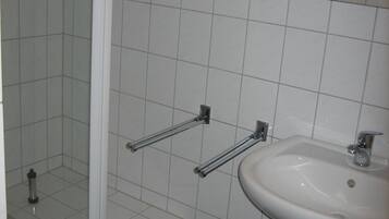 Ett badrum med dusch, handfat och spegel.
