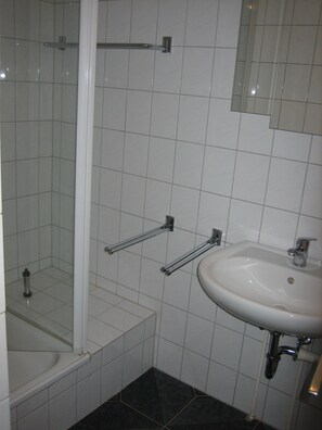 Un baño con ducha, lavamanos y espejo.