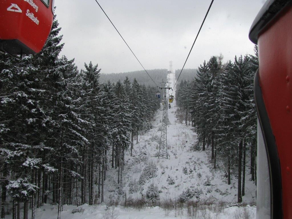 A snowy forest path with a cable car in the distance.