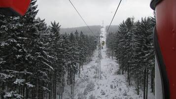 A snowy forest path with a cable car in the distance.