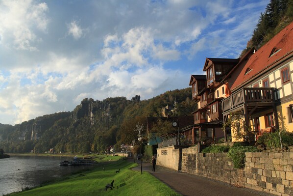 A riverside walkway with stone walls and traditional buildings with balconies.