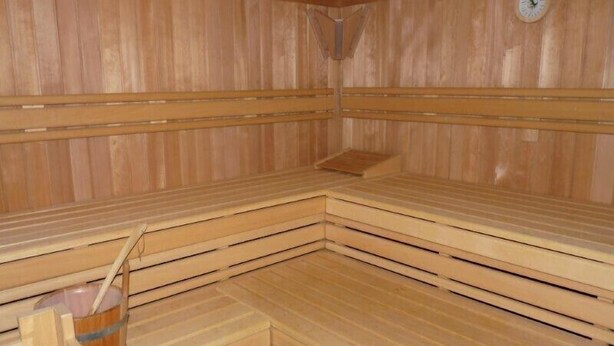 Uma sauna com bancos de madeira e um relógio na parede.