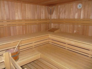 A sauna with wooden benches and a clock on the wall. - Sylt / Westerland, modern 2-Zi ground floor apartment - close to the beach and the center, WLAN (Westerland)