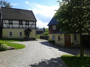 A traditional half-timbered house with a cobblestone driveway leading to a wooden gate. - Vacation where you can sleep peacefully with the window open (Rechenberg-Bienenmühle OT Holzhau)