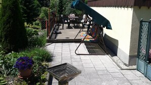 An outdoor patio with a grill, seating area, and a covered table.