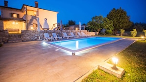 A swimming pool with lounge chairs and a stone wall. - Private and secure 5000 sqm garden, pool, children's playground, only 9 km from the sea (Nedešćina)