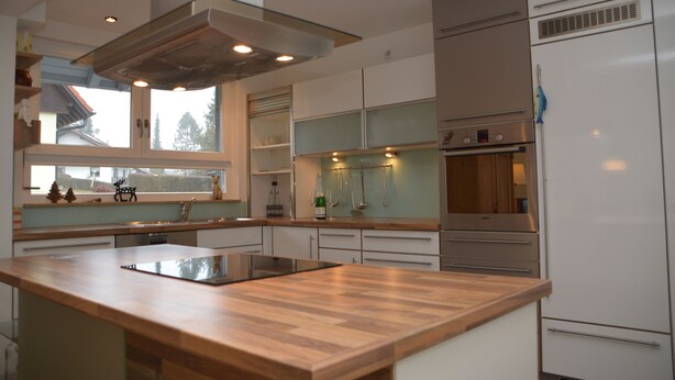 A modern kitchen with a central island, stainless steel appliances, and a window providing a view of the outside.