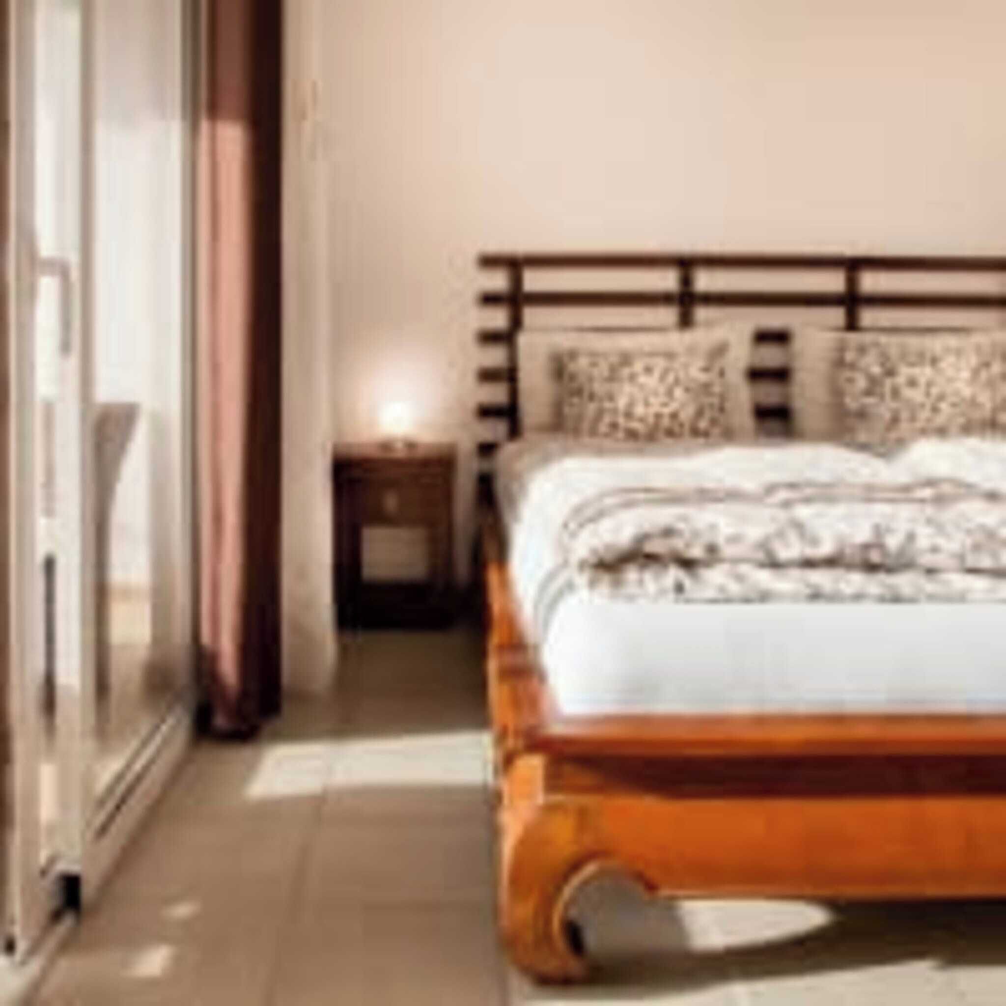 A bedroom with a wooden bed, a nightstand, and a sliding glass door.