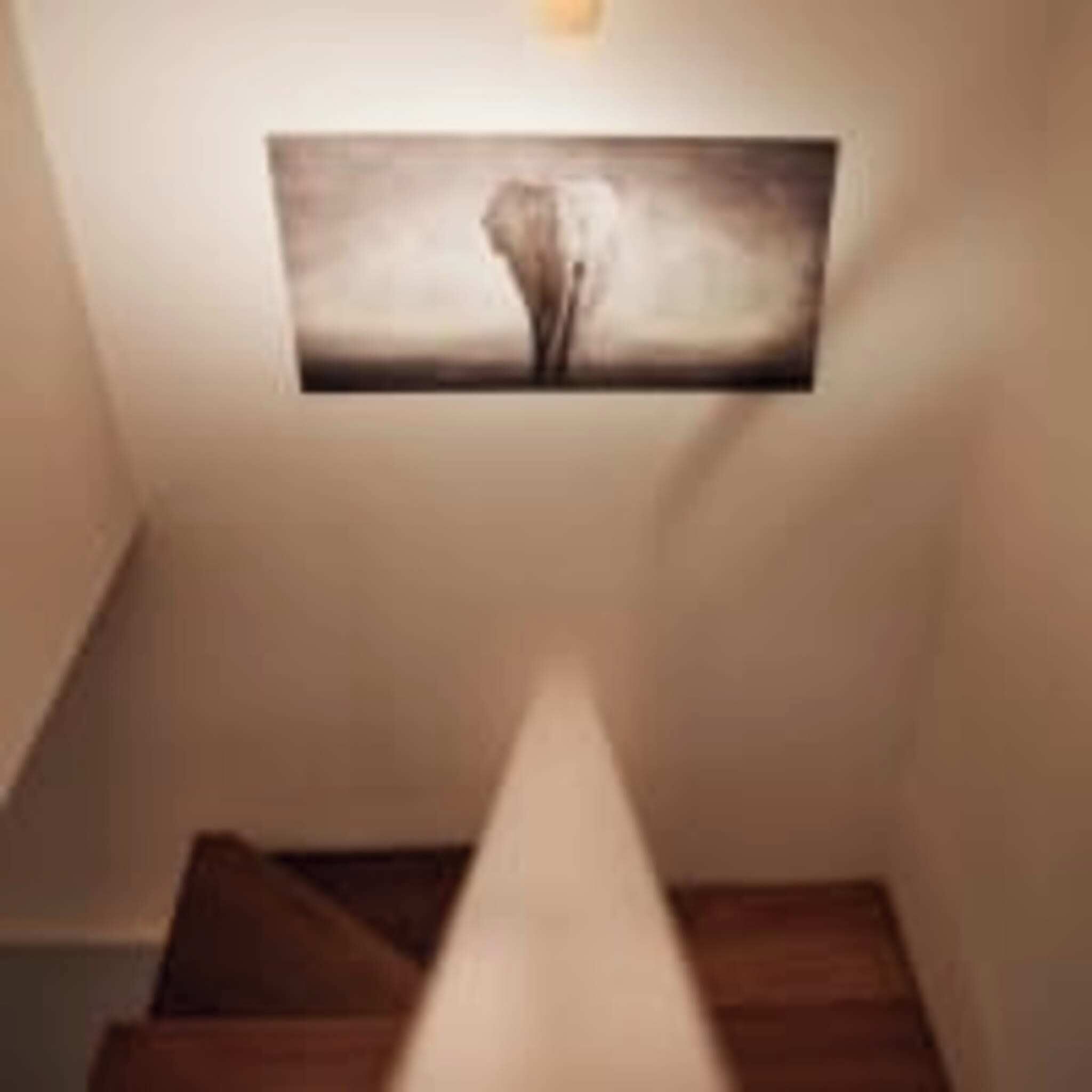Una escalera con una obra enmarcada en la pared superior.