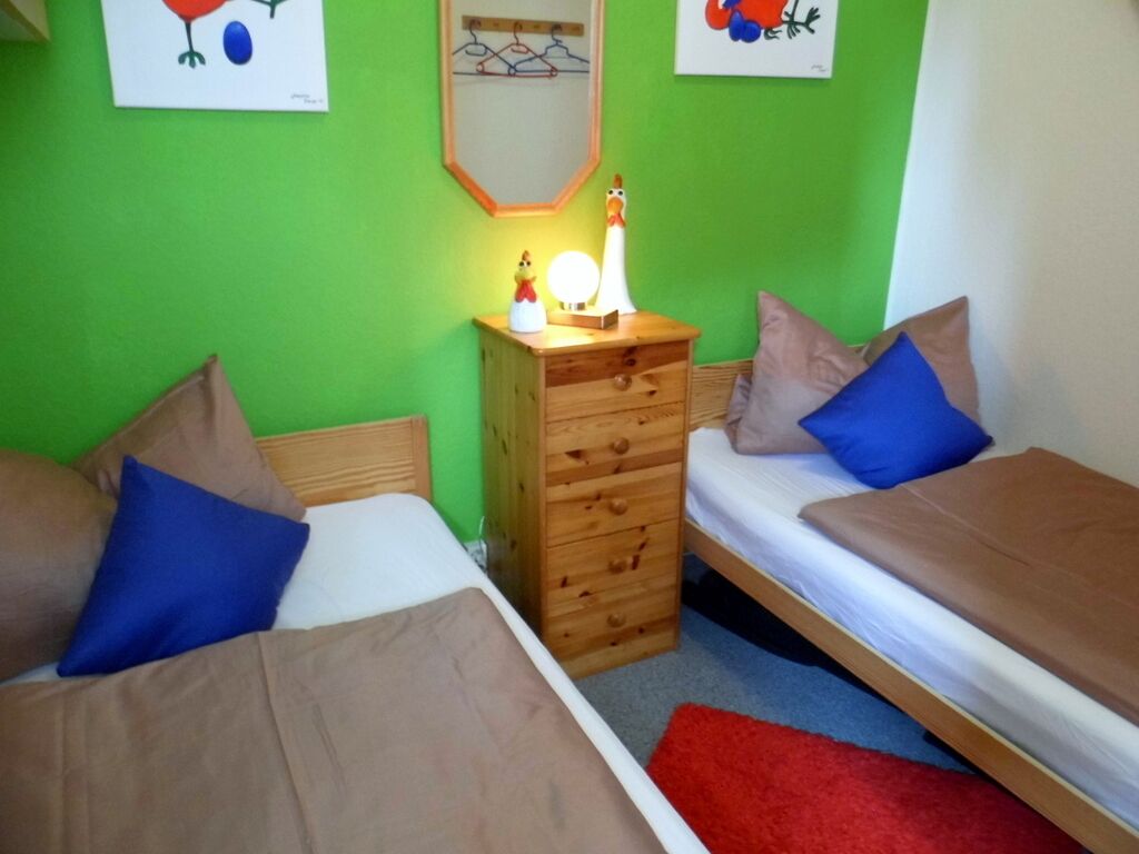 A room with two single beds, a wooden dresser, a mirror, and artwork on the walls.