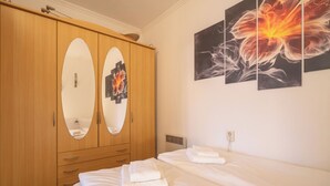 Habitación de hotel con un armario de madera, dos camas y obras de arte en la pared.