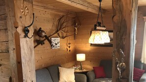 Interior acogedor de una cabaña de madera con un sofá, una mesa y una lámpara colgante.