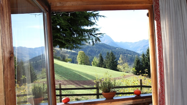 Un balcón de madera con vistas a un valle verde y montañas.