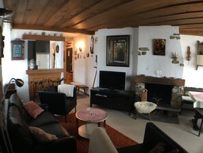 A cozy living room with a fireplace, a television, and a dining area. - Vacation apartment w/south-west balcony, fireplace, pool & an underground garage (Davos)