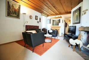 A living room with a fireplace, a television, and a sofa. - Vacation apartment w/south-west balcony, fireplace, pool & an underground garage (Davos)