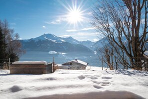 Un paysage enneigé avec une maison et des montagnes en arrière-plan.