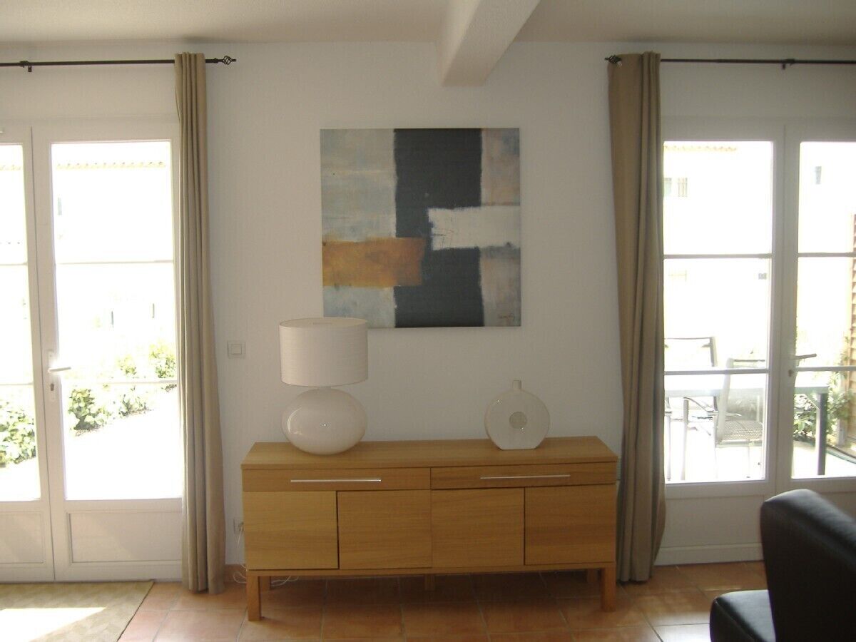 A room with a wooden cabinet, a lamp, and a painting on the wall.