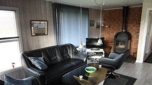 A modern living room with a leather sofa, a glass coffee table, a fireplace, and a television.