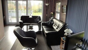 A modern living room with a black leather sofa, a black armchair, and a glass coffee table.