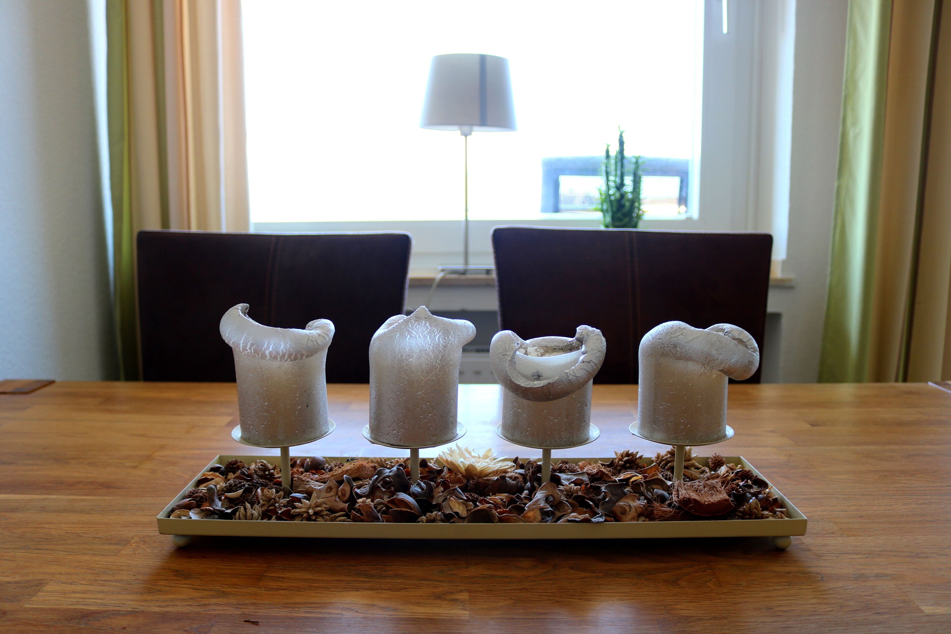 Une assiette contenant quatre gourmandises enrobées de chocolat, posée sur une table en bois, avec une fenêtre en arrière-plan.