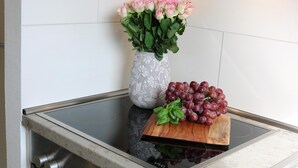 A kitchen with a built-in oven, a countertop with a vase of flowers and grapes, and a wooden cutting board. - 1A apartment, 2-4 people, very close to the beach, central, large garage, family friendly (Sylt)