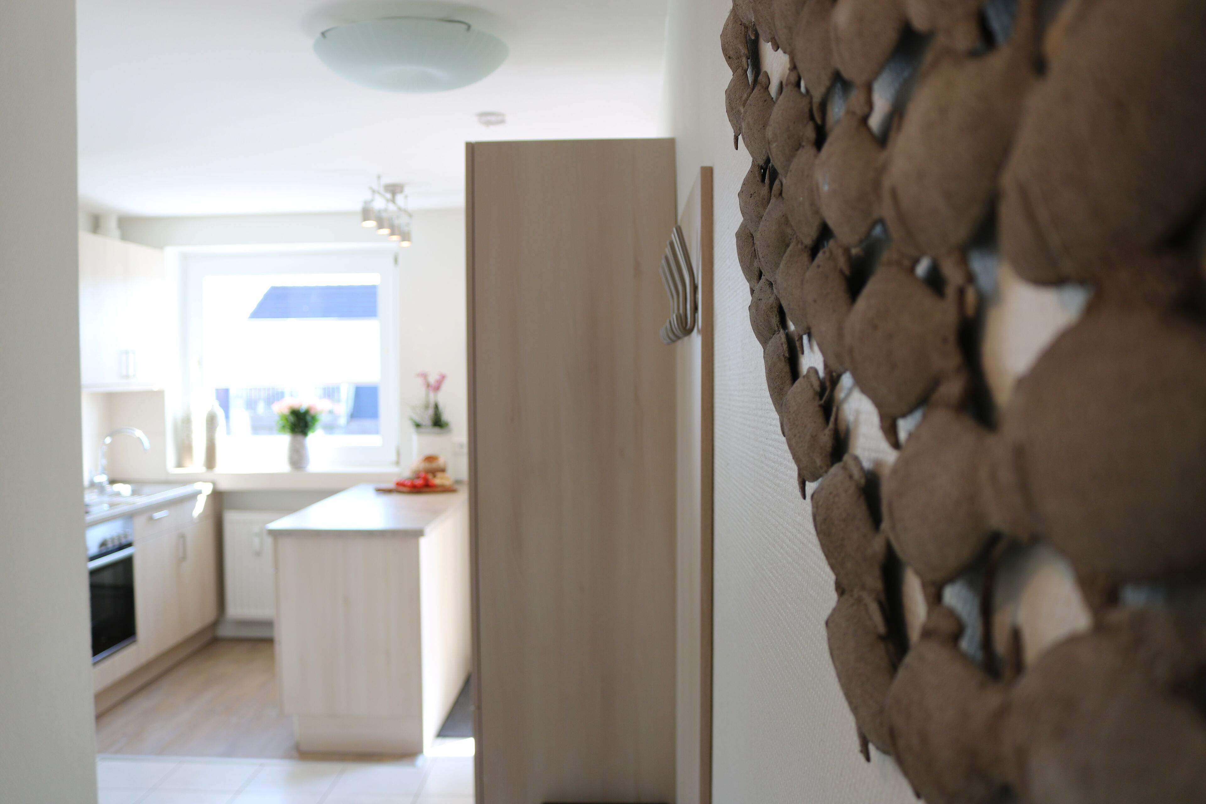 A modern kitchen with white cabinetry, a central island, and a view of the dining area.