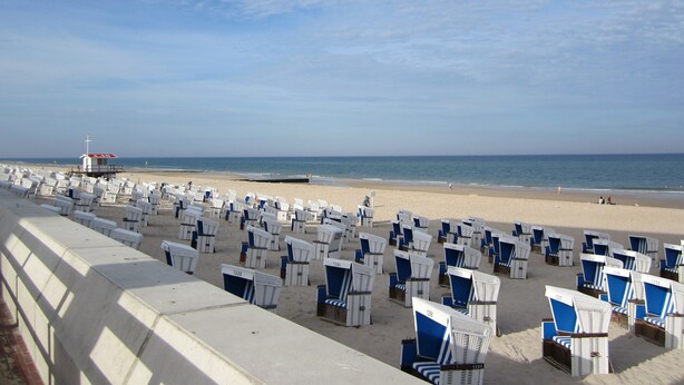 A beach with rows of white and blue beach chairs and a lifeguard tower in the background. - 1A apartment, 2-4 people, very close to the beach, central, large garage, family friendly (Sylt)