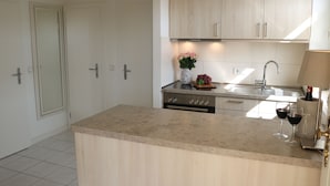 A modern kitchen with light wood cabinets, a central island, and a built-in oven. - 1A apartment, 2-4 people, very close to the beach, central, large garage, family friendly (Sylt)