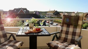 A balcony with a table set for two, featuring a bottle, a glass, and a plant. - 1A apartment, 2-4 people, very close to the beach, central, large garage, family friendly (Sylt)