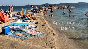 A crowded beach with people sunbathing and swimming.