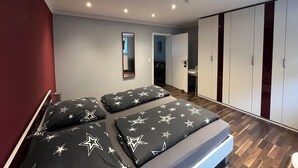 Een moderne slaapkamer met een bed, stersoppen, een spiegel en een kledingkast.