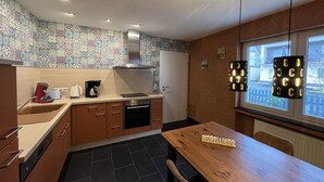 Een kleine keuken met een houten tafel, een koffiezetapparaat en een fornuis.