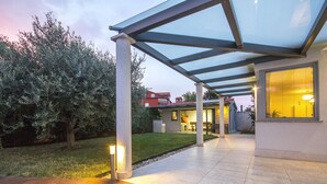 Un espace extérieur abrité comprenant une terrasse, une véranda et une entrée bien éclairée.
