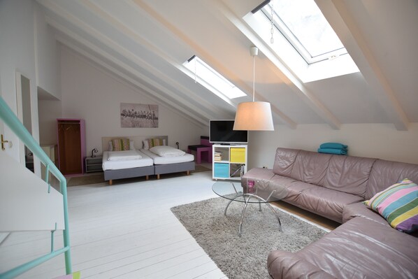 A spacious loft bedroom with a large skylight, a cozy seating area with a sofa and armchair, and a small table. - rainbow loft 9 in the heart of Kreuzberg (Bezirk Friedrichshain-Kreuzberg)