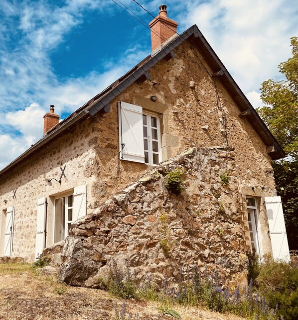 A rustic stone house with a steeply pitched roof, white shutters, and a chimney. - Charming old stone house in the Morvan, tastefully restored, comfortable  (WLAN) (Cussy-En-Morvan)
